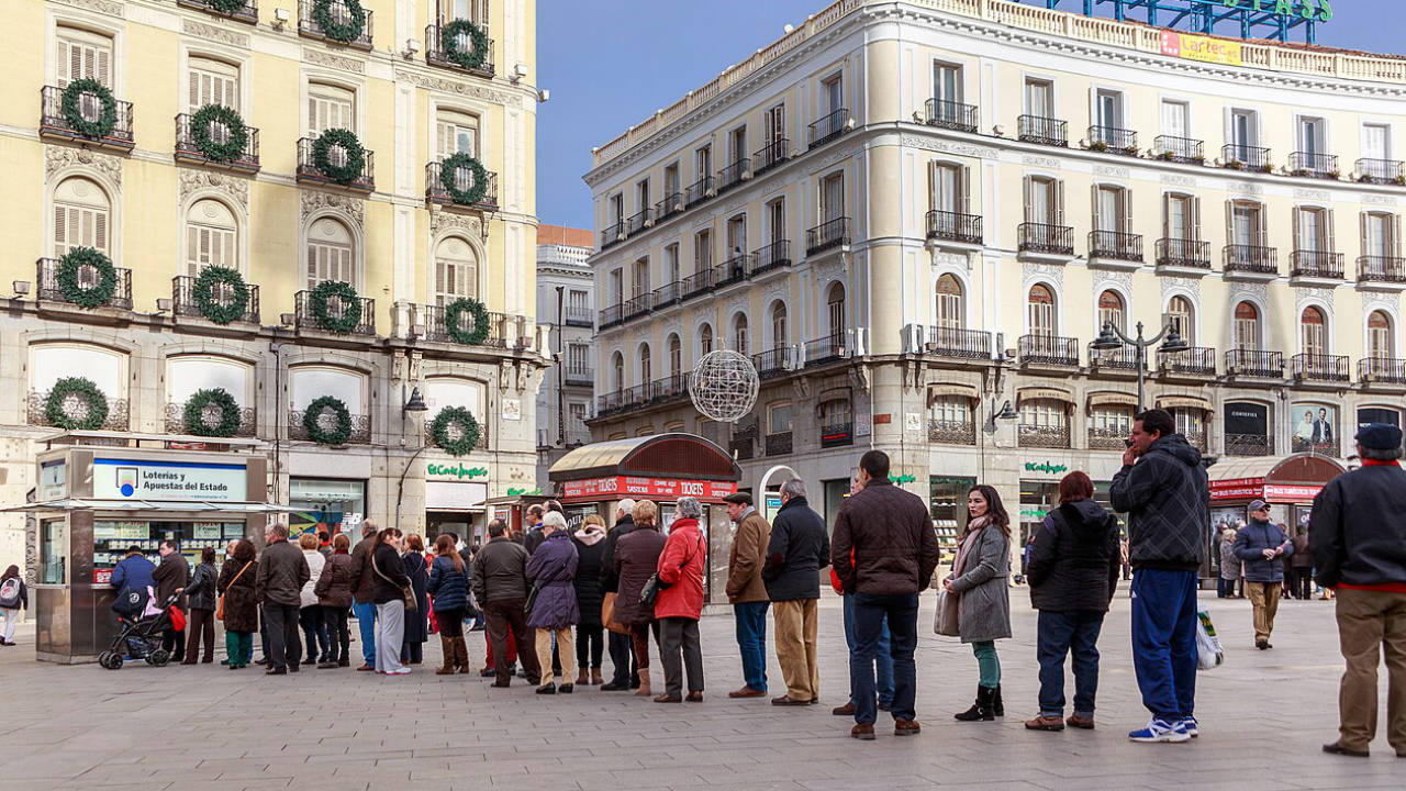Gente haciendo cola comprando lotería de Navidad en Madrid